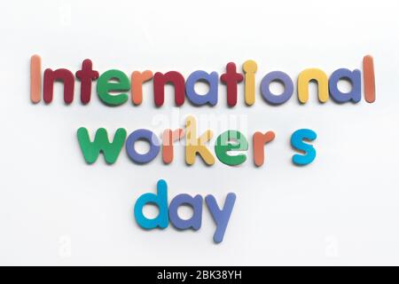 Internationaler Workers` Day Text in mehrfarbiger Schrift auf weißem Hintergrund mit Baureparaturwerkzeugen. Schild „Labor Day Concept“. Tag der internationalen Arbeiter.` Stockfoto